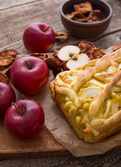 Apple pie on a board with fresh apples