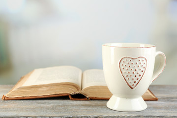 Cup of tea and book on table, on light background