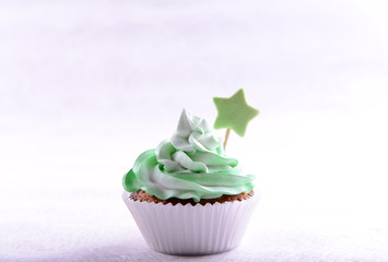 Delicious cupcake with inscription on table on beige background