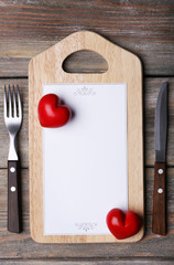 Cutting board with menu sheet of paper and hearts