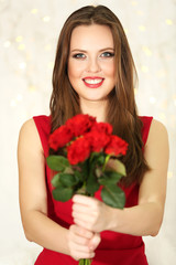 Smiling girl with bouquet of red roses on lights background