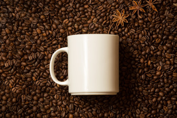 white mug against coffee beans with anise stars lying like steam