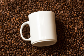 white mug lying on roasted coffee beans