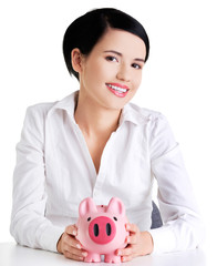 Fototapeta na wymiar Happy businesswoman holding piggy bank