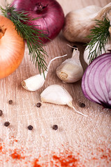 close up of garlic, onion fresh herbs on  wooden board