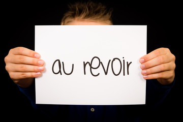 Child holding sign with French word Au Revoir - Goodbye