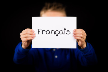 Child holding sign with French word Francais - French
