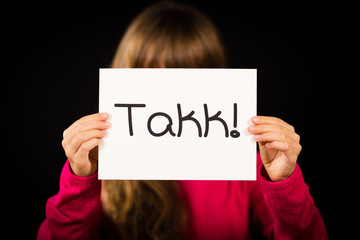 Child holding sign with Norwegian word Takk - Thank You