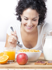 Woman eating a healthy breakfast with cereals at morning on bed