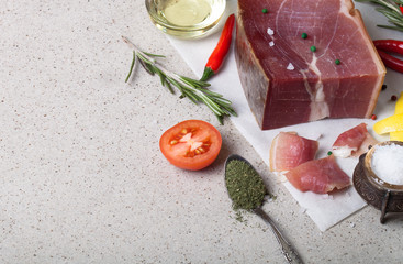 Jamon with herbs and spices, salt, olive oil and tomatoes on sto
