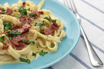 Fresh and beautiful fettuccine carbonara on blue plate.