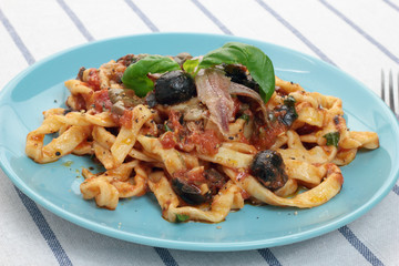 Blue plate of freshly cooked fettuccine puttanesca.