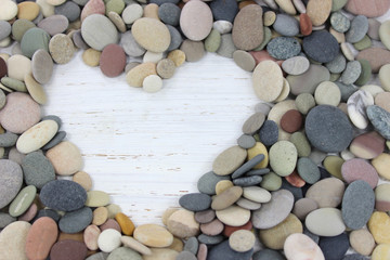 Heart shape made with pebbles on a white distressed wood backgro
