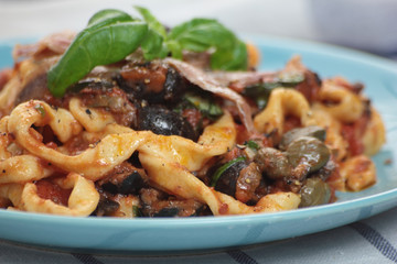 Blue plate of freshly cooked fettuccine puttanesca.