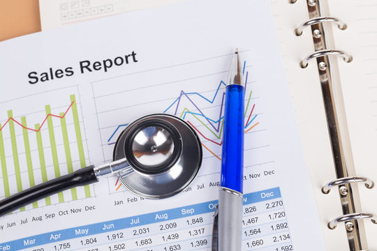 sheet of annual sales report with stethoscope