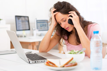 Young attractive student eating salad while phoning