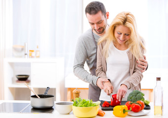 Young attractive man helping out his wife while cooking