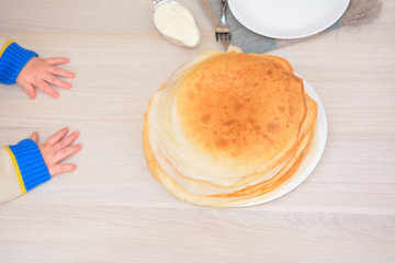 toddler's hands on the table next to the stack of pancakes