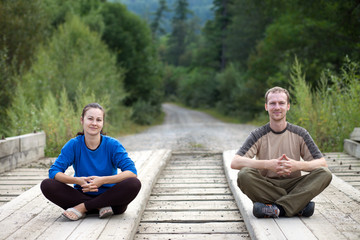 Tourist couple sitting on a wooden bridge
