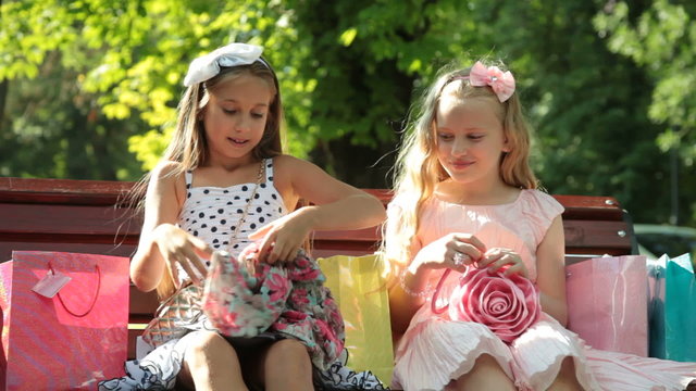 Fashion little girls with shopping bags on a bench