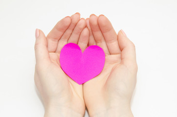 Women's hands holding a pink heart