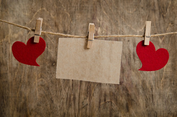 Red fabric hearts with sheet of paper hanging on the clothesline