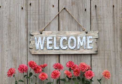 Welcome sign with row of mums by wood fence