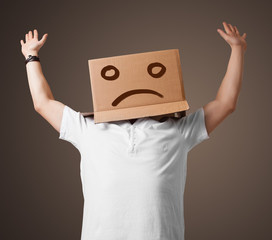 Young man with a brown cardboard box on his head with sad face