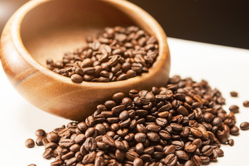 Heap of Brown Roasted Coffee Beans in Wooden Bowl on White Surfa