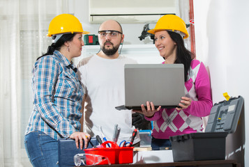 Craftsman and two craftswoman looking at laptop, selective focus