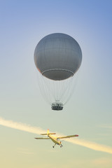 Fototapeta premium Gas Balloon and Yellow Aircraft against the Sky