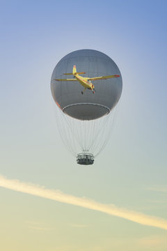 Gas Balloon and Yellow Aircraft against the Sky