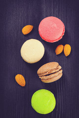 toned photo of Colorful French macaroons on a dark rustic wooden