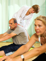 Yoga instructor showing asana to mature couple