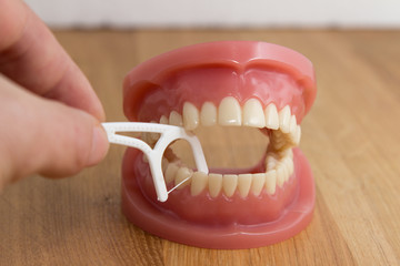 Man cleaning false teeth with dental floss