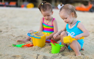 Adorable little girls playing with beach toys during summer