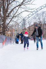 Adorable little girl and happy father on skating rink outdoor