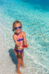 Little adorable girl with sea star at the tropical beach