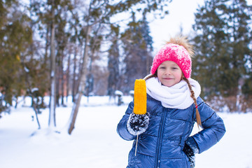 Little adorable girl with sweet corn at winter park