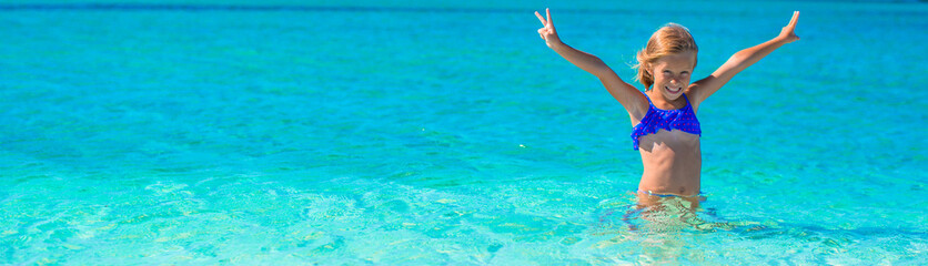 Little girl having fun on tropical beach with white sand and