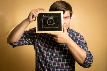 handsome young man holding camera drawn on small blackboard