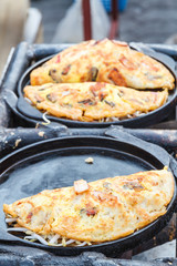 Oysters fried in egg batter on frying pan in the market.