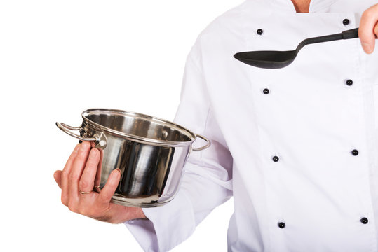 Chef's hand holding stainless steel pot and spoon