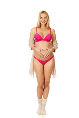 Obraz premium Pregnant woman making heart shape