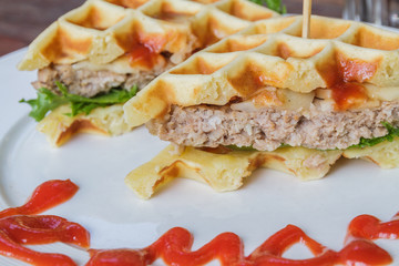 Hamburger made with waffles and pork on white plate.