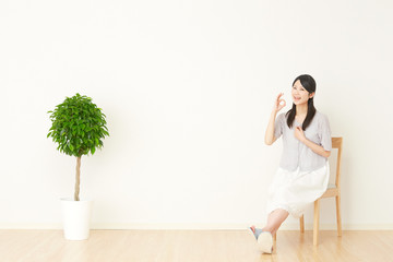 部屋でOKサインする女性