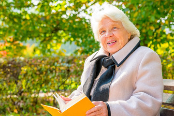 elderly woman with a book resting on a bench