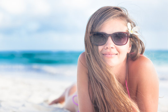 long haired young woman in bikini and sunglasses on tropical