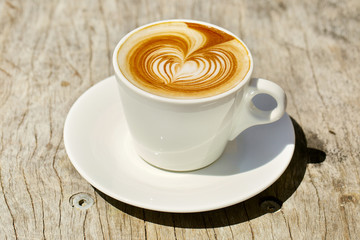 Cappuchino or latte coffe in a white cup with heart shaped foam