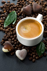 cup of espresso on coffee beans background and chocolate candies